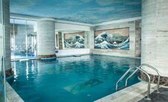 a modern indoor swimming pool with a mural of the great wave off kanagawa on the wall , and a diving board at Super Hotel Candle