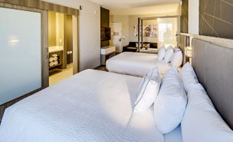 a modern hotel room with two white beds , each topped with a white comforter and pillows , accompanied by a kitchenette and a bathroom at SpringHill Suites Dayton Vandalia