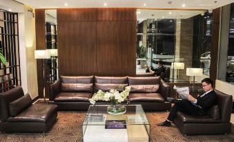 a living room with a brown leather couch , glass coffee table , and a wooden wall at Brentwood Suites