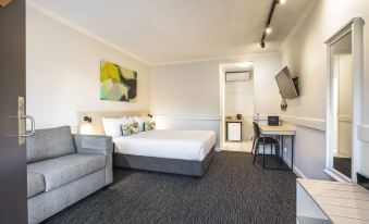 a modern hotel room with a white bed , couch , and desk , along with a kitchenette area at Nightcap at Matthew Flinders Hotel