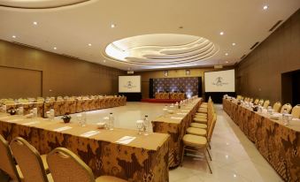 a large conference room with multiple rows of chairs arranged in a semicircle , and a podium at the front of the room at The Singhasari Resort Batu