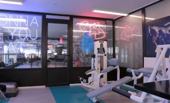 a modern gym with various exercise equipment , including a treadmill and a stationary bike , as well as neon signs on the walls at Hamra Urban Gardens