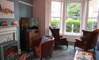 a living room with two leather chairs , a television , and a window with greenery outside at The Linden Leaf Rooms - Classy & Stylish