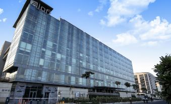 "a modern , glass - fronted building with the word "" iide "" on top and a clear blue sky in the background" at Aloft New Delhi Aerocity