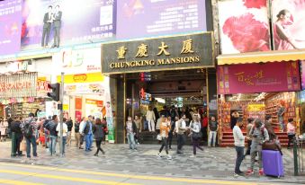 There is a crowd walking down the street in front, and there is an oriental store on one side at Hong Kong Budget Hostel