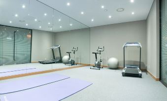 There is a spacious room with multiple exercise equipment and a yoga mat in the center at Hotel Venue-G Seoul