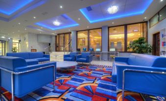 a modern hotel lobby with blue and red carpet , blue chairs , and white coffee table at Alexandra Hotel