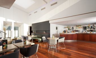 a modern , open - concept living room with wooden floors and furniture , including a dining table , chairs , and a couch at Holiday Inn Lille - Ouest Englos