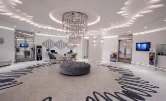 a luxurious hotel lobby with white walls , black and white striped flooring , and a large chandelier hanging from the ceiling at Wyndham Grand Istanbul Kalamış Marina Hotel