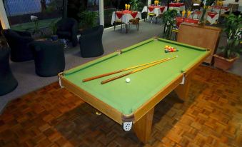 a pool table with a green felt surface and wooden legs is set up in an outdoor area at Lindy Lodge Motel