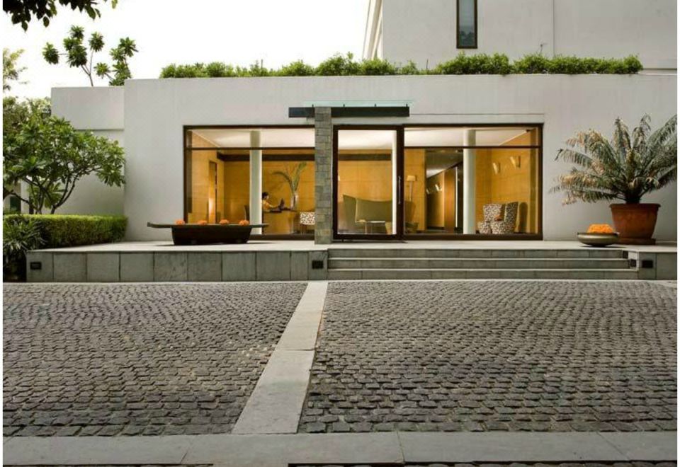 a modern building with a large window and a cobblestone path in front of it at The Manor - New Delhi