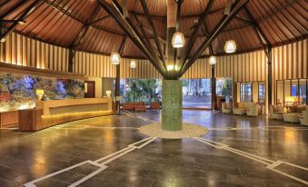 a spacious hotel lobby with a large tree in the center , surrounded by chairs and couches at Aston Sunset Beach Resort - Gili Trawangan