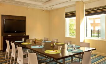 a dining room with a long wooden table set for a meal , surrounded by chairs at Aloft Chesapeake