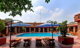 a large outdoor swimming pool surrounded by lounge chairs and umbrellas , providing a relaxing atmosphere for visitors at Faisalabad Serena Hotel