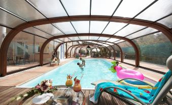 a group of people are enjoying a swim in an indoor pool with a glass enclosure at Mercure Castres l'Occitan