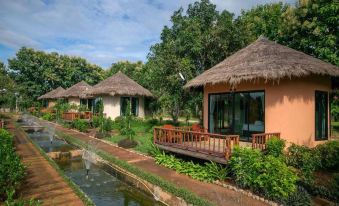 a serene rural landscape with several thatched - roof houses , surrounded by lush greenery and a river at Aurora Resort Chiangdao