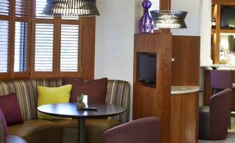 a modern hotel lobby with wooden furniture , including couches and chairs , creating a cozy and inviting atmosphere at Courtyard Rochester Brighton