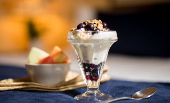 a dessert in a glass dish with whipped cream and blueberries is presented on a blue napkin at The Landing Hotel