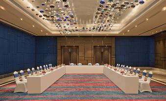 a long table is set with multiple vases and bottles , while two doors are visible in the background at Sheraton Grand Bengaluru Whitefield Hotel & Convention Center