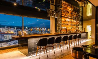 a modern bar with a view of the city , featuring black chairs and a long wooden counter at Octant Ponta Delgada
