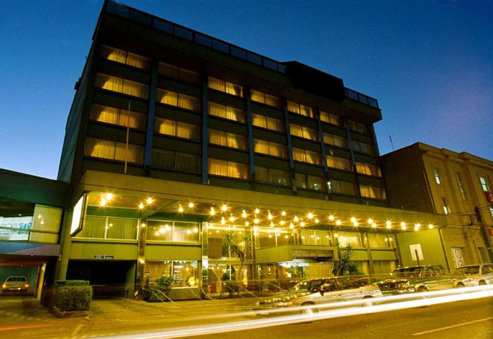 a large hotel building with many windows , surrounded by trees and lit up at night at Hotel Frontera Clasico