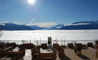 a couple is taking a photo of the mountains and a large body of water , with the sun shining brightly in the background at Le Mirador Resort and Spa