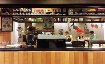 a group of people working behind a counter in a coffee shop , preparing drinks and interacting with customers at Go Hotel