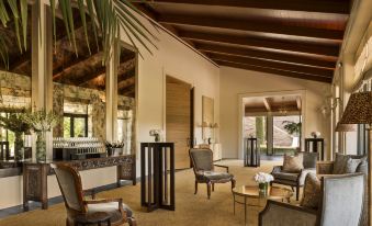 a spacious living room with wooden furniture , including a couch , chairs , and a dining table at Rosewood Sand Hill
