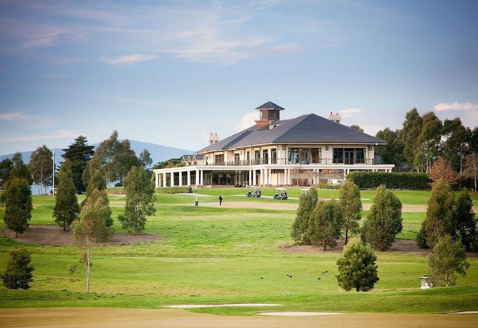 a large building with a brown roof is surrounded by trees and grass on a golf course at Yarra Valley Lodge, an EVT Hotel