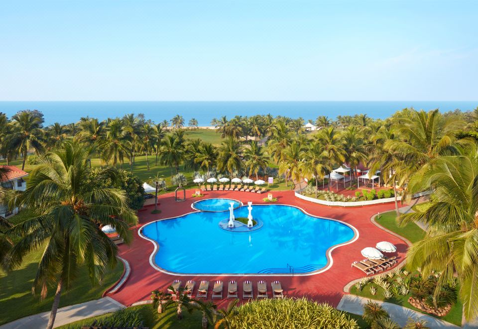 an aerial view of a resort with a large pool surrounded by palm trees , chairs , and umbrellas at Holiday Inn Resort Goa