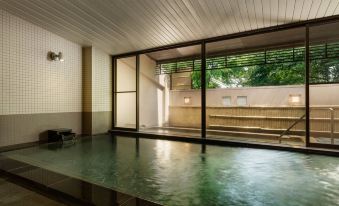 a modern indoor pool with large windows , reflecting the surrounding environment and surrounding trees , as well as a bench and wooden dividers at Courtyard by Marriott Hakuba