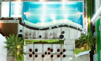 a large outdoor swimming pool surrounded by lush greenery , with several lounge chairs placed around it at Hotel 101 Manila