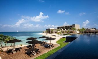 a beautiful beach resort with a large pool , umbrellas , and sun loungers , surrounded by the ocean at Nizuc Resort & Spa