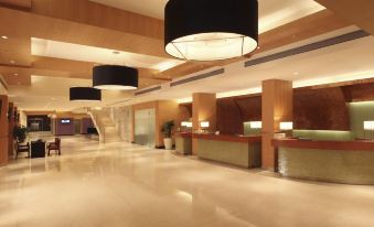 a large , well - lit hotel lobby with a reception desk and several chairs arranged around it at Novotel Mumbai Juhu Beach