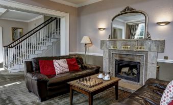 a living room with a leather couch , coffee table , and chess board on the floor at The Knaresborough Inn - the Inn Collection Group