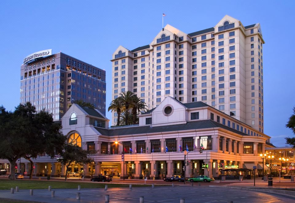 a large hotel building with a palm tree in front of it , surrounded by other buildings at Signia by Hilton San Jose