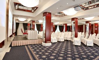 a large conference room with rows of chairs arranged in a semicircle , and a podium at the front of the room at Mediterranean Hotel