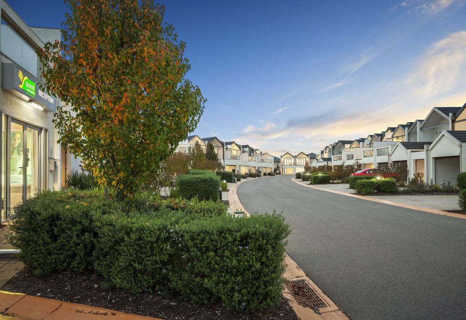 a residential area with a row of houses and a street lined with trees and bushes at Quest Sanctuary Lakes