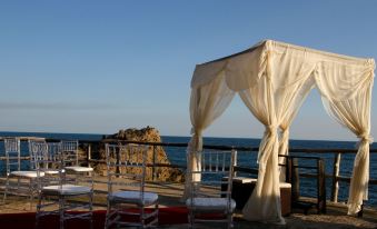 a wedding ceremony taking place on the beach , with chairs set up for guests to sit and listen to the ceremony at Atami Escape Resort