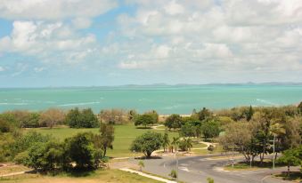 a beautiful view of a city with lush green trees and a clear blue sky , overlooking a body of water at Pacific Sands Apartments Mackay
