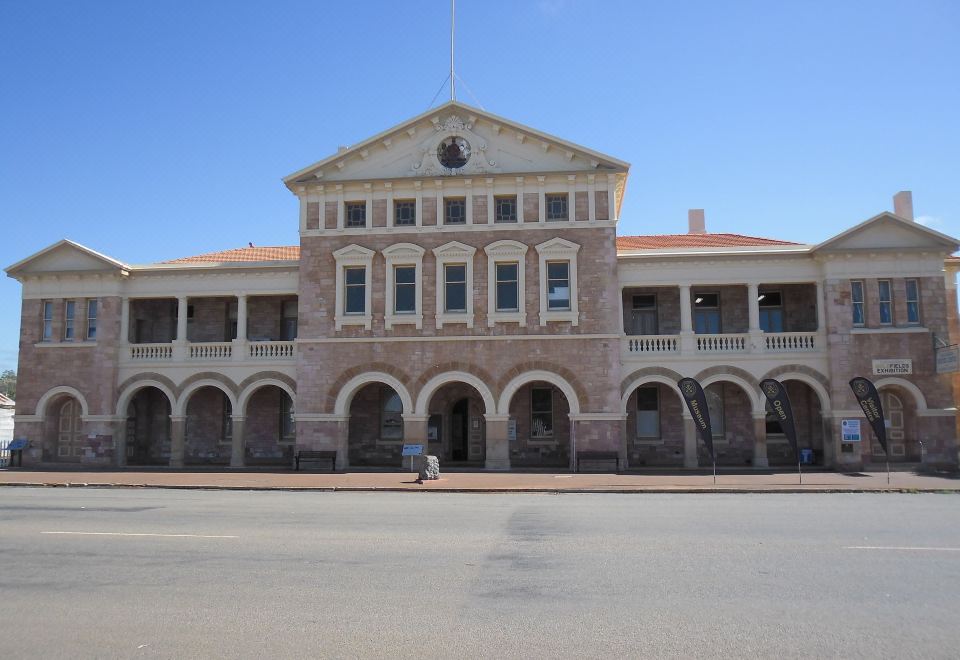 a large , old brick building with a clock tower on top , situated in a city square at Coolgardie GoldRush Motels