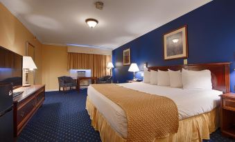 a large bed with a gold blanket is in the middle of a room with blue walls and a desk at Best Western White House Inn