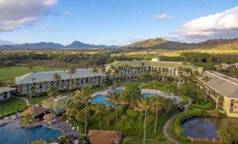 a bird 's eye view of a resort with pools , palm trees , and mountains in the background at OUTRIGGER Kaua'i Beach Resort & Spa