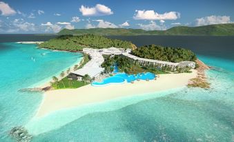 a luxurious resort with a large pool surrounded by lush greenery , mountains , and clear blue water at Daydream Island Resort