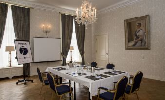 a large , well - lit conference room with a white table and multiple chairs arranged for a meeting at Fletcher Hotel Paleis Stadhouderlijk Hof