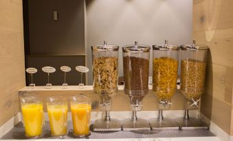 a buffet table with multiple glass jars filled with various food items and beverages , including orange juice at Hotel Gran Via