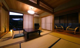 a room with a table and chairs , large windows , and a window with wooden blinds at Yufuin Bath Satoyamasafu