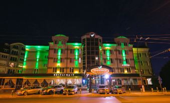 a large building with green and white lights on it , surrounded by cars and people at Vila Verde