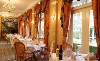 a dining room with a table set for a meal , featuring white tablecloths and wine glasses at Coulsdon Manor Hotel and Golf Club