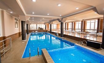 an indoor swimming pool with a blue water surface and surrounding facilities , including wooden flooring and glass windows at Well Hotel and Spa